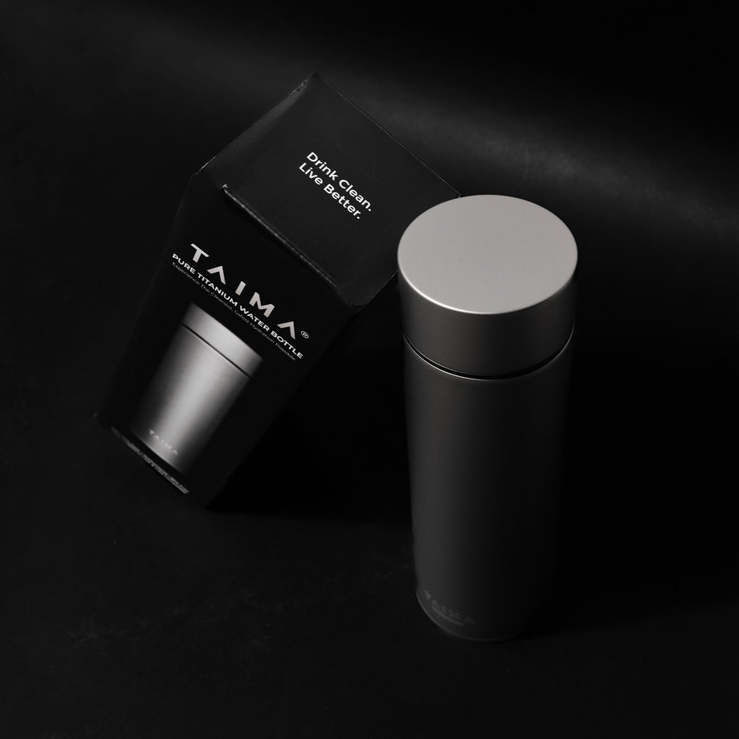 Black Taima water bottle with packaging on a dark background